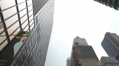 New York City, New York, ABD - 08.01.2024: Parlak gökyüzü altındaki çağdaş yüksek binaların alçak açılı görüntüsü. Gösterişli mimaride yansıtıcı cam ve kentsel tasarım elementleri yer alıyor..