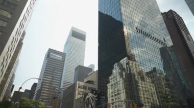 Bu resim New York 'ta yansıtıcı cam cepheli gökdelenleri gösteriyor. Yansımalar, kentsel bir ortamda modern ve geleneksel mimarinin karışımını vurguluyor..