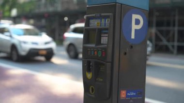 New York City, New York, ABD - 08.01.2024: Yoğun bir şehir caddesinde arka planda araçların geçtiği bir parkmetre belirgin bir şekilde duruyor. Kamuya açık park etmenin kolaylığını vurguluyor.