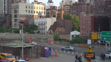 New York City, New York, ABD - 08.01.2024: Görüntü Ed Koch Queensboro Köprüsü yakınlarında tarihi binalar, tabelalar ve trafik altyapısı bulunan bir kentsel alan gösteriyor. Bisikletçiler ve araçlar