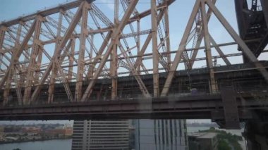 New York 'taki Queensboro Köprüsü' nün karmaşık çelik iskeletinin detaylı bir görüntüsü. Şehir ve nehre karşı çekilen köprü yapısı endüstriyel tasarımını ön plana çıkarıyor.