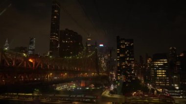 Queensboro Köprüsü, karmaşık tasarımı ve parlak ışıklarıyla geceleri ışıl ışıl parlıyor. Manhattan silueti arka planda parlıyor, nefes kesici bir şehir manzarası yaratıyor..
