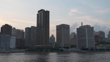 Görüntü, Queensboro Köprüsü 'nü güneş batarken suyun üzerinde uzanırken yakalıyor. Gökdelenleri ve şehir yapılarını çevreleyen ikonik köprüyü huzurlu bir akşam ışığında çevreleyen.