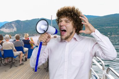 Portrait of a young excited expressive man with curly hair in white shirt screams out something in megaphone. Tourist people on the yacht boat in the background. clipart