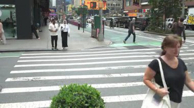 New York City, New York, ABD - 07.29.2024: Değişen yaşlardaki insanlar Times Meydanı 'nda gün ortasında kalabalık bir caddeyi geçtiler. Canlı şehir atmosferi çevredeki dükkanlar ve trafik tarafından vurgulanıyor.