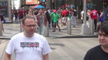 New York City, New York, ABD - 07.29.2024: Güneşli bir günde ziyaretçiler canlı bir atmosferi keşfederken ve tadını çıkarırken kalabalık Manhattan 'daki Times Meydanı' nı dolduruyor. Hevesli insanlar paylaşır