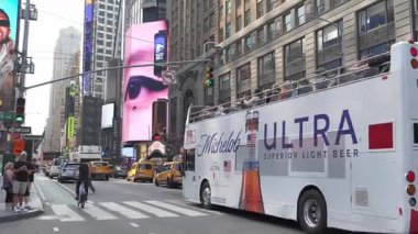 New York, New York, ABD - 07.29.2024: İkonik sarı taksiler ve parlak dijital reklam panoları ile çevrili, kalabalık Manhattan sokaklarında çift katlı bir tur otobüsü geziniyor. Dolu dolu bir gün.