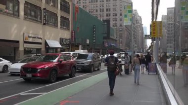 New York City, New York, ABD - 07.29.2024: Manhattan 'da hareketli bir cadde yayalar, araçlar ve mağaza vitrinleri ürünleri sergiliyor. Canlı şehir atmosferi her gün yakalıyor.