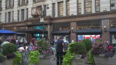 New York City, New York, ABD - 07.29.2024: İnsanlar Manhattan 'da canlı çiçekler ve dükkanlarla çevrili bir kafede toplanıp sosyalleşiyorlar. Manhattan 'ın merkezindeki ünlü Macy mağazası..