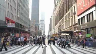 New York City, New York, ABD - 07.29.2024: Kalabalık güneşli bir öğleden sonra trafiğin yoğun olduğu Manhattan kavşağında yol alır. Canlı atmosfer, enerjiyi yakalar.