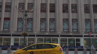 New York City, New York, ABD - 07.29.2024: Yayalar Manhattan 'ın işlek caddeleri boyunca yürür, Empire State Binası' nın yanından geçer. Sarı taksiler insanlar günlerini canlı bir şekilde geçirirken geçiyor.