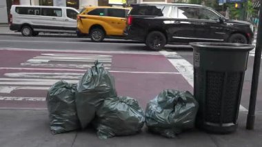 New York City, New York, ABD - 07.29.2024: Manhattan 'da kaldırıma çöp torbaları yığılıyor ve şehrin karşı karşıya olduğu atık yönetimi sorunlarını gösteriyor. Yaya geçitlerinde yürürken,