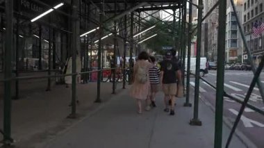 New York, New York, New York, ABD - 07.29.2024: İnsanlar Manhattan 'da bir kaldırım boyunca yürürken yoğun bir inşaat alanında geziniyorlar. Yayalar ve yayalar ile hareketli şehir hayatı açıkça görülür.