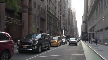 New York City, New York, ABD - 07.29.2024: Öğleden sonra güneş ışığı yüksek binaların arasından geçerken arabalar Manhattan caddesini işgal ediyor. Canlı bir şehir atmosferi New York şehrinin yaşamını gözler önüne seriyor.