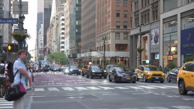 New York, New York, New York, ABD - 07.29.2024: İnsanlar New York 'ta kalabalık bir kavşakta yürüyor, trafik ve yüksek binalarla çevrili. Canlı şehir sahnesinde sarı taksiler, modern