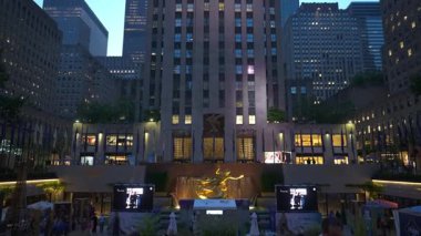 New York City, New York, ABD - 07.29.2024: The Rockefeller Center akşamları şehir ışıklarıyla aydınlanan ve yüksek gökdelenlerle çevrili olarak dimdik ayakta duruyor. Art Deco mimarisi parlıyor