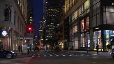 New York, New York, New York, ABD - 07.29.2024: Bir çöp kamyonu Manhattan 'ın kalabalık bir caddesinde geceleri atık topluyor. Trafik kamyonun boşalmasını beklerken şehir ışıkları çevreyi aydınlatıyor.