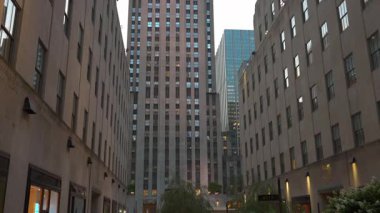 New York 'taki Rockefeller Center' da iki tarihi bina tarafından çerçevelenmiş yüksek bir gökdelen. Simetrik perspektif, modern cam cepheleriyle klasik taş cepheleri arasındaki zıtlığı vurgular.