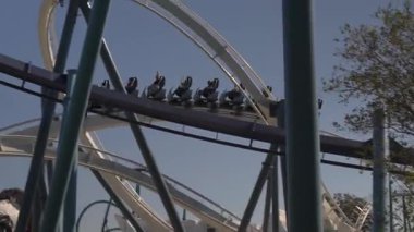 Macera parkındaki lunapark treninde heyecan verici bir sürüş deneyimi. Sürücüler açık mavi gökyüzüne karşı havada süzülür, eğlenceli ve heyecanlı bir günün tadını çıkarırlar..