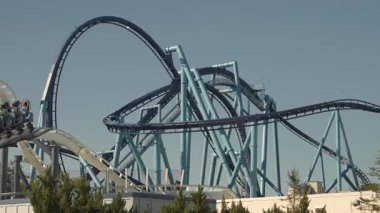 Heyecan arayanlar, açık mavi gökyüzünün altındaki lunaparkta keyifli bir lunaparkta hız treninin tadını çıkarıyorlar. Döner ve döner, nefes kesici manzaralar sunar ve adrenalin pompalar eğlence.