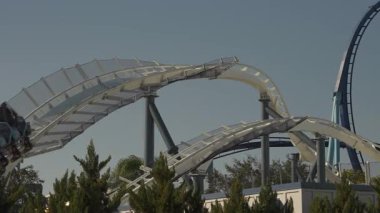 Heyecan verici lunapark trenleri deniz temalı bir parkta açık mavi gökyüzüne çarpıp dönüyor. Ziyaretçiler heyecan verici aktivitelerden ve çevrenin çarpıcı manzaralarından keyif alabilirler..