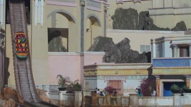 Orlando, Florida, ABD - 11.15.2024: Heyecan verici bir tekne gezisi temalı bir park su gösterisinde gerçekleşti. Heyecanlı yolcular ellerini kaldırırken tekne devasa bir su duvarı oluşturuyor..