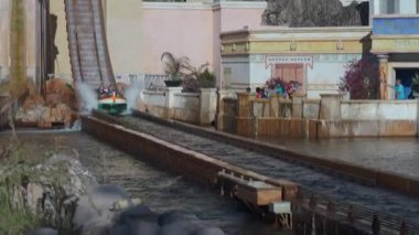 Orlando, Florida, ABD - 11.15.2024: Bir tekne tema parkı gezisi sırasında suya daldı, büyük bir sıçrama yarattı. Seyirciler akvaryumun girişindeki heyecan verici anı izliyorlar..