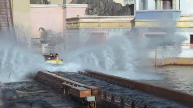 Orlando, Florida, ABD - 11.15.2024: Konuklar Deniz Dünyası 'nda heyecan verici bir su yolculuğunun tadını çıkarıyorlar. Bir tekne dramatik bir şekilde aşağı süzülür, bir su banyosu gönderir. Aile ve arkadaşlar arka planda tezahürat eder ve güler..