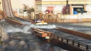 Orlando, Florida, ABD - 11.15.2024: Hevesli ziyaretçiler, teknenin dalgalar arasında dalgalanması, heyecan ve kahkaha yaratırken büyük bir sıçramaya hazırlanarak su yolculuğuna çıktılar. Aile eğlencesi ve macera için mükemmel bir gün..