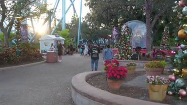 Orlando, Florida, ABD - 11.15.2024: Ziyaretçiler renkli tatil süslemeleriyle süslenmiş bir deniz parkında geziniyorlar. Neşeli atmosfer aileleri eğlenmeye ve mevsimlik kutlamalara davet ediyor..