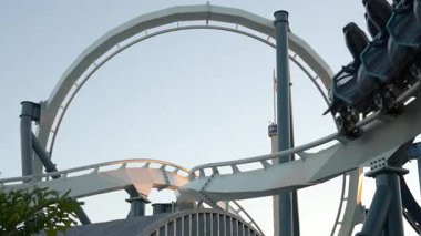 Deniz kenarındaki bir lunaparkta hız trenine binmenin heyecanını yaşayın. Güneş batıyor, bu eğlence dolu yerin macera ve atmosferini arttırıyor..