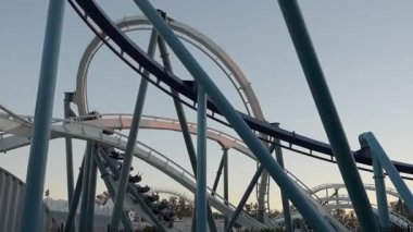 Sürücüler, gün batımında lunaparktaki büyük bir lunaparktaki hız treninde heyecan verici dönüşler yaşar ve bu heyecan verici macera için canlı bir zemin oluştururlar..