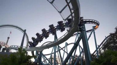 Güneş deniz eğlence parkının arkasında batarken hız treninde motorcuların heyecandan çığlık atmasını izleyin. Adrenalin ve canlı atmosferi hisset..