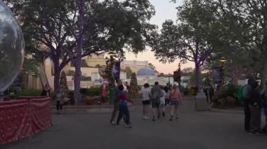 Orlando, Florida, ABD - 11.15.2024: Ziyaretçiler güneş batarken Deniz Dünyası 'nda şenlikli dekorasyonlarla çevrili canlı bir atmosferin keyfini çıkarıyorlar. İnsanlar güzel ışıklandırılmış alanda geziniyor, manzaranın ve seslerin tadını çıkarıyor..