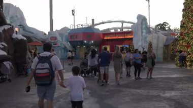Orlando, Florida, ABD - 11.15.2024: Aileler, Deniz Dünyası 'nın tatil temalı bölgesinde hafif gösteriler ve kış süslemeleriyle çevrili olarak geziniyorlar. Atmosfer eğlence ve neşeli ziyaretçilerle dolu..