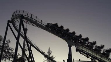 Heyecan arayanlar, macera parkında hızlı bir lunapark treninde heyecan verici bir yolculuk yaşarlar. Güneş batarken, bu heyecan verici dönüşler ve dönüşler için çarpıcı bir zemin hazırlarlar..