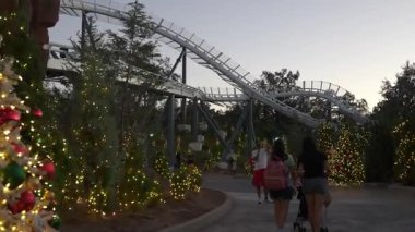 Orlando, Florida, ABD - 11.15.2024: Aileler, şenlikli ışıklar ve bayram süslemeleriyle donatılmış bir şekilde Deniz Dünyası parkında akşam yürüyüşünün tadını çıkarıyorlar. Gece çöktüğünde havada gezinti heyecanı.