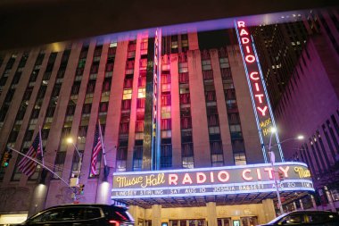 New York City, New York, ABD - 07.28.2024: Radio City Music Hall Manhattan 'da canlı neon ışıklarıyla parlıyor. Ünlü New York şehri Amerikan bayrakları ve renkli tabelasıyla göze çarpıyor..