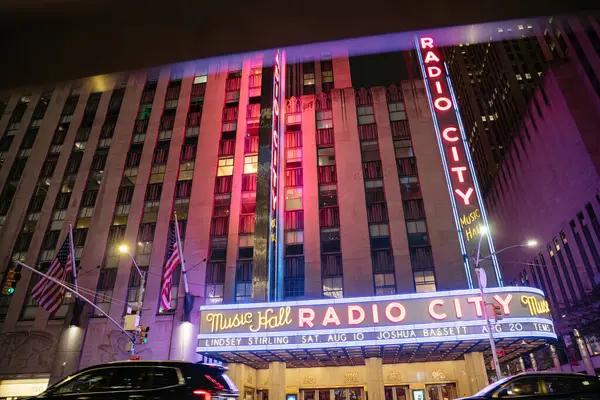 New York City, New York, ABD - 07.28.2024: Radio City Music Hall Manhattan 'da canlı neon ışıklarıyla parlıyor. Ünlü New York şehri Amerikan bayrakları ve renkli tabelasıyla göze çarpıyor..