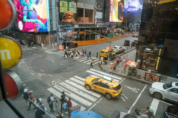 New York City, New York, ABD - 07.29.2024: İnsanlar New York Times Meydanı 'ndaki yaya geçidinden geçiyor. Turistler hareketli şehirde dolaşırken, klasik sarı bir taksi kavşakta bekliyor..