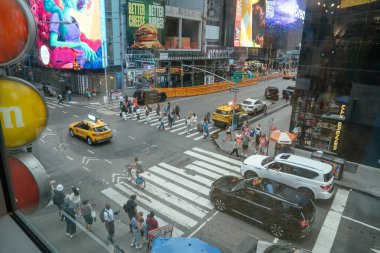 New York City, New York, ABD - 07.29.2024: Bir bisikletçi trafiği ve Times Meydanı 'ndaki insanları geçiyor. Yoğun bir yaya geçidi sarı taksiler, reklam panoları ve ikonik NYC enerjisiyle çevrilidir..