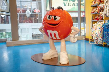 New York City, New York, ABD - 07.29.2024: New York 'taki MM mağazasında kırmızı MM karakterinin tam vücut heykeli duruyor. Etrafı mavi zemin üzerinde mallarla çevrili..