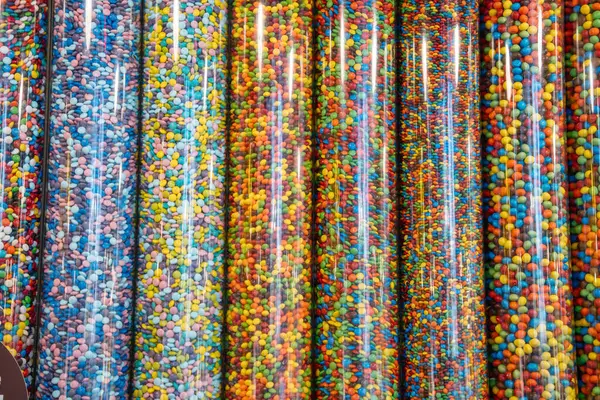 New York City, New York, ABD - 07.29.2024: Perakende şekerleme dükkanında renkli bonibonlar ile dolu uzun dikey borular. Her tüp farklı bir renk taşır..