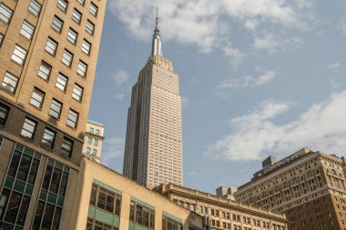 Çevresindeki binaların üstündeki ikonik Empire State Binası. Fotoğraf, açık bir günde sivri uçlu kulesini ve detaylı pencerelerini yakalar..