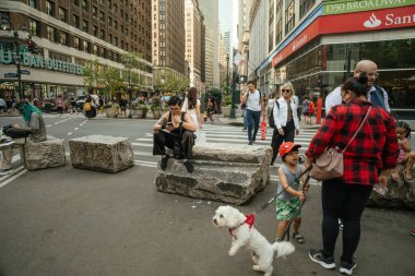 New York City, New York, ABD - 07.29.2024: Köpeği olan bir çocuk ve diğer insanlar New York sokaklarında yürüyüp toplanıyorlar. Yoğun köşe bir şehir ortamında binalar ve dükkanlarla çevrilidir..