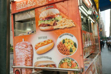New York, New York, New York, ABD - 07.29.2024: Yemek arabasında yayalar için hamburgerler, sosisliler ve pirinç tabakları yer alıyor. New Yorklular tipik şehir yaşamının ortasında yürüyorlar.