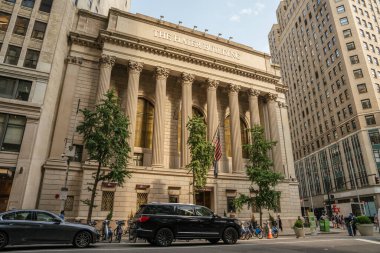 New York City, New York, ABD - 07.29.2024: Bu ikonik bina uzun neoklasik sütunlara ve büyük bir cepheye sahiptir. İnsanlar şehir merkezinde cadde boyunca yürürken arabalar geçer..