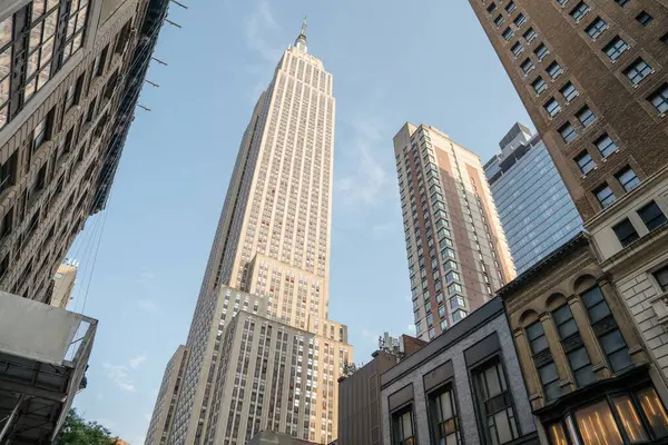 Manhattan 'ın göbeğindeki Empire State Binası kuleleri. Açık mavi gökyüzü ve akşam ışığı mimariyi ve şehir atmosferini vurgular..