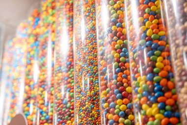 Uzun şeffaf borular parlak ve renkli şeker katmanlarıyla doludur. Yakından çekilen görüntü, popüler çikolatanın canlı dokularını ve renklerini yakalıyor..