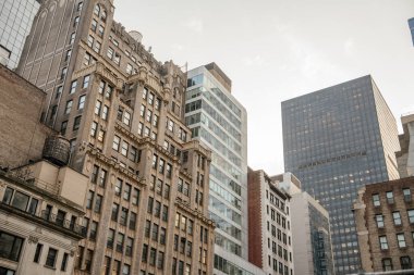 Detaylı cepheli bir dizi tarihi tuğla bina Manhattan şehir merkezindeki modern cam kulelerin yanında duruyor. Öğleden sonra güneşi mimari dokulara ve karşıtlıklara sıcaklık katar..